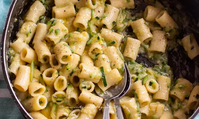 Primo piatto di pasta con pancetta e zucchine, condito con una crema saporita e pepe nero.