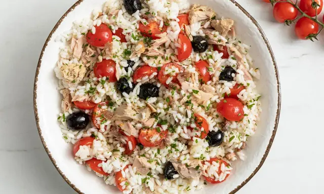 Insalata di riso con tonno, pomodorini, olive nere e prezzemolo. Un'idea fresca e gustosa su come condire l'insalata di riso per un pranzo estivo.