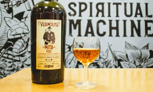 Bottiglia di vermouth rosso Mita e un bicchiere pieno. Scopri come si fa il vermouth con questo aperitivo.