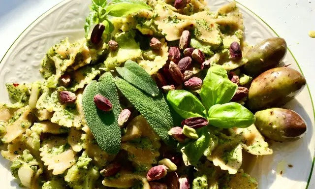 Farfalle condite con un saporito pesto di salvia, guarnite con pistacchi, basilico e olive verdi.