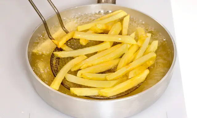 Patate fritte dorate che sfrigolano nell'olio bollente, pronte per essere gustate.