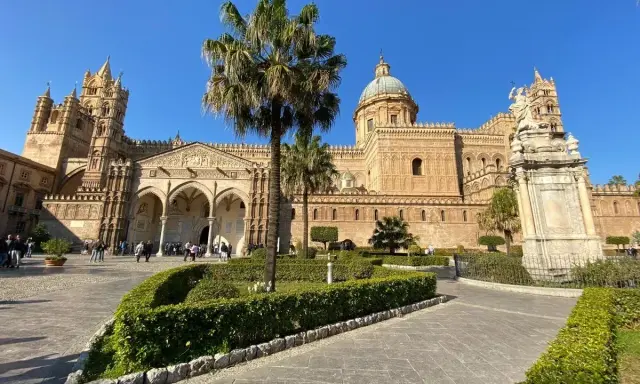 Il percorso per Palermo inizia con la maestosa Cattedrale, tra palme e giardini curati, sotto un cielo azzurro.