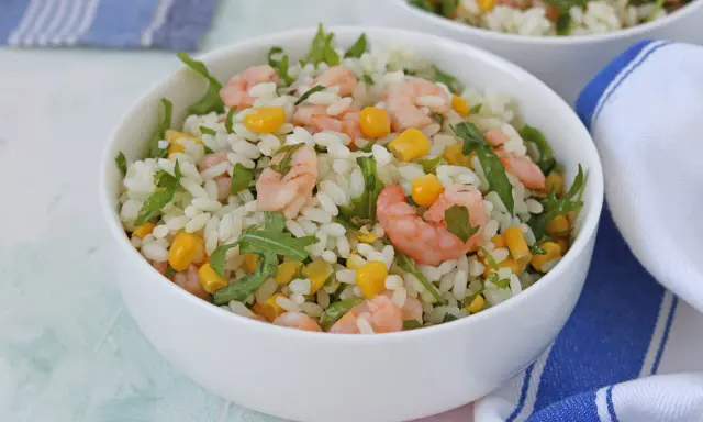 Insalata di riso con gamberetti, mais e rucola, un piatto fresco e colorato, servito in una ciotola bianca.