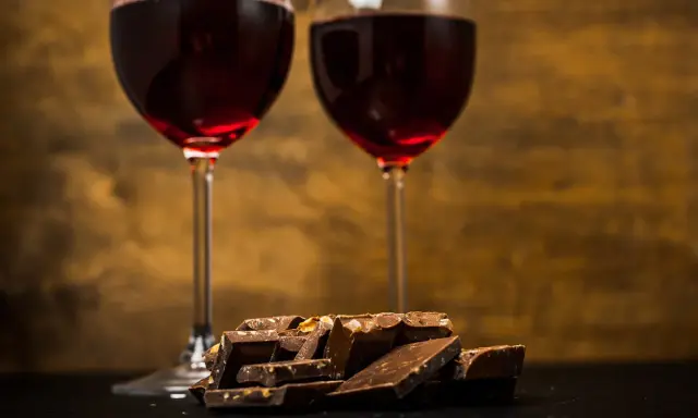 Due calici di vino rosso e una pila di cioccolato fondente, un perfetto abbinamento vino e cioccolato per un momento di piacere.