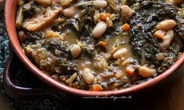 Un piatto fumante di ribollita toscana, con fagioli cannellini, cavolo nero e pane raffermo in un'autentica ciotola di terracotta.