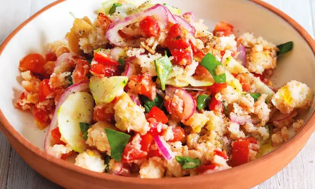 Panzanella ricetta: un'insalata estiva con pane raffermo, pomodori, cetrioli, cipolla rossa e basilico, condita con olio d'oliva.