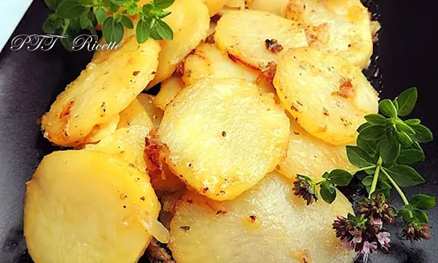 Patate e cipolle in padella, dorate e profumate, guarnite con rametti di origano fresco.