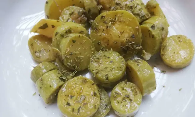 Zucchine trombetta cotte al forno, condite con erbe aromatiche e olio. Un contorno saporito e leggero.