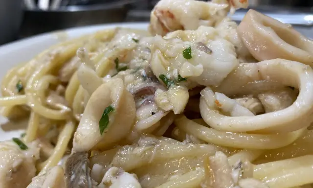 Spaghetti con sugo di pesce, ricchi di calamari e gamberi, un piatto che profuma di mare.