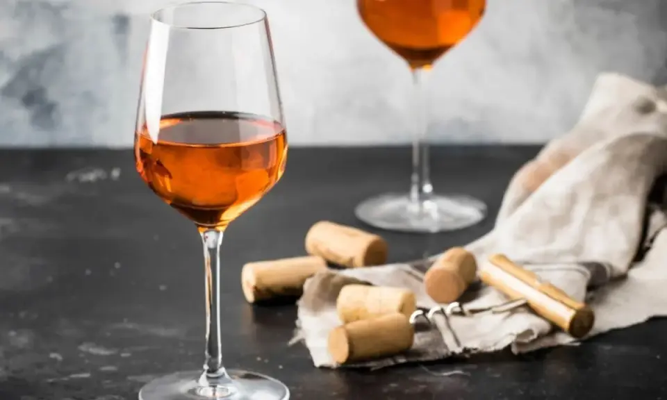 Calici di vino arancione, un'introduzione a cosa sono questi vini unici. Tappi e cavatappi completano la scena.