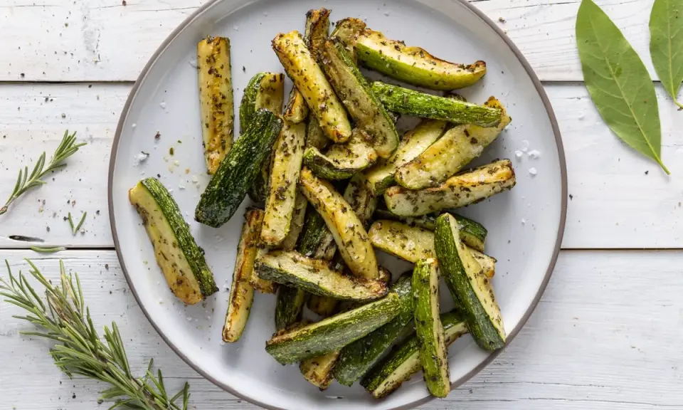 Zucchine in friggitrice ad aria, tagliate a bastoncini e condite con erbe aromatiche, pronte per essere gustate.