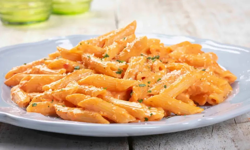 Penne cremose con salsa rosa, un'ottima idea per un pranzo veloce. Spolverata di parmigiano e prezzemolo fresco.