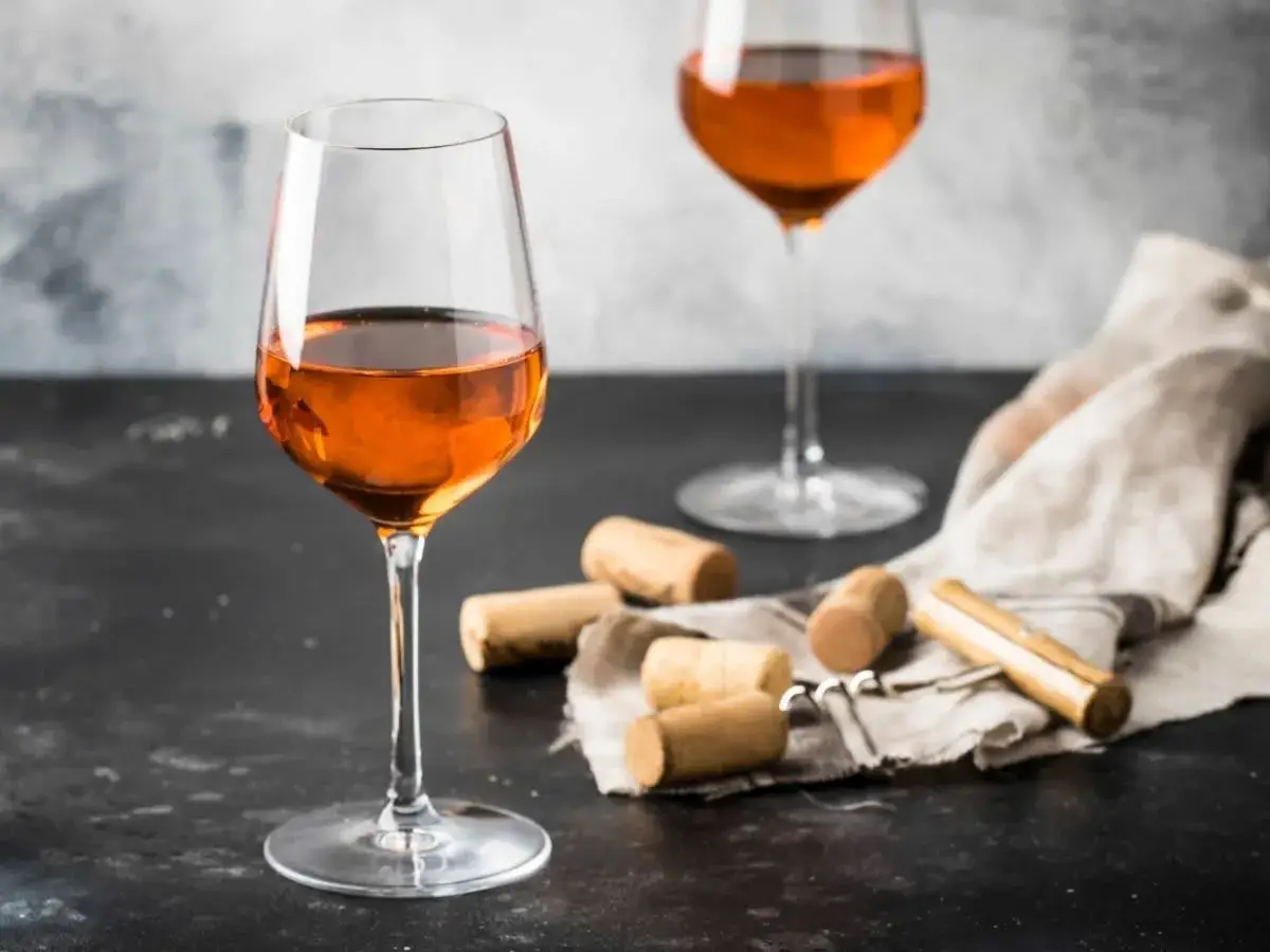 Calici di vino arancione, un'introduzione a cosa sono questi vini unici. Tappi e cavatappi completano la scena.