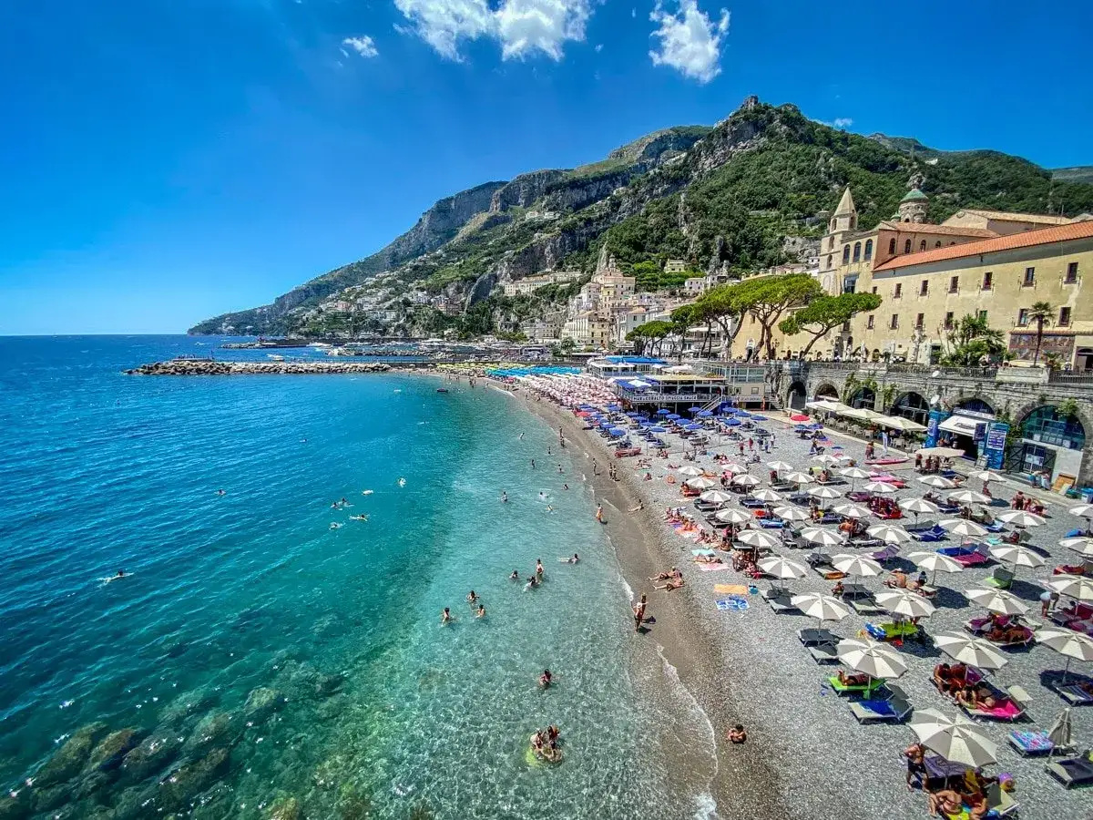Spiaggia affollata con ombrelloni e mare cristallino, perfetta per scoprire le città italiane da visitare in 3 giorni.