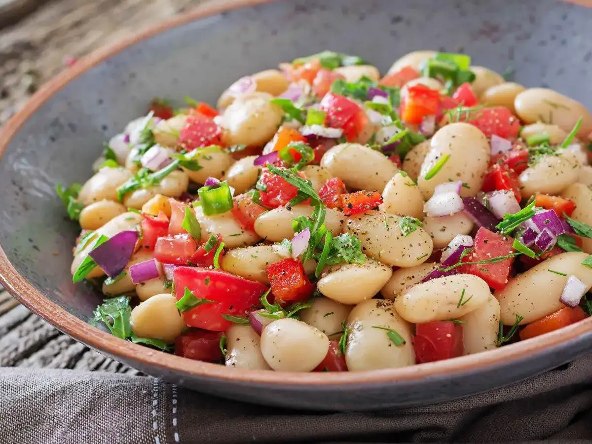 Insalata fresca e colorata con fagioli cannellini, pomodori, cipolla rossa e erbe aromatiche. Un'idea per gustose fagioli cannellini ricette.