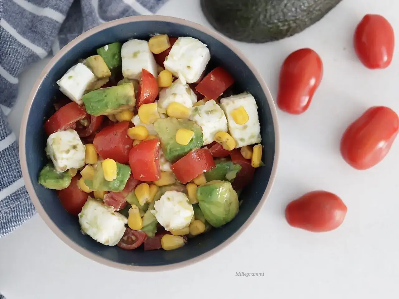 Insalata fresca con avocado, pomodorini, mais e cubetti di formaggio. Un piatto colorato e gustoso.