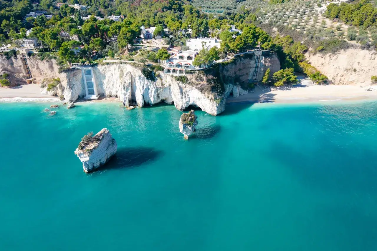 Scogliere bianche a picco sul mare turchese, con rocce isolate e vegetazione lussureggiante. Sembra la spiaggia pi&ugrave; bella della Puglia.
