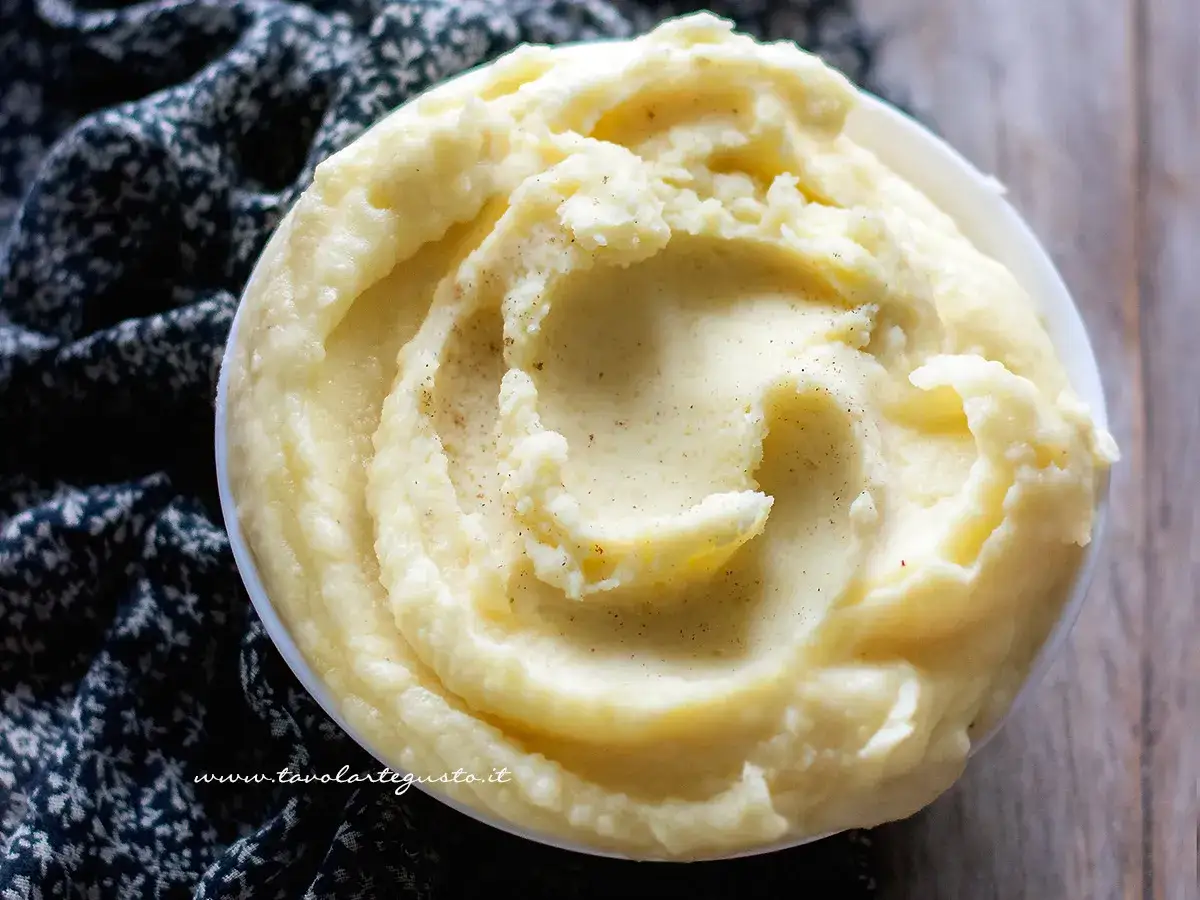 Una ciotola di cremosa crema di patate, soffice e invitante, con un pizzico di pepe nero. Perfetta per accompagnare ogni piatto.