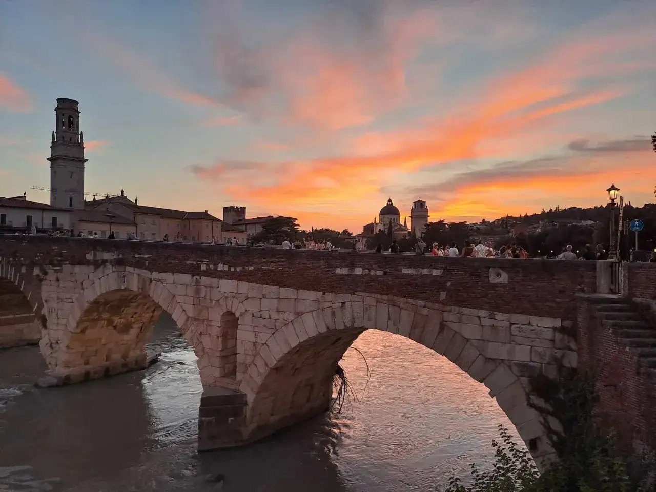 Tramonto infuocato su Ponte Pietra, un'icona di Verona. Perfetto per scoprire cosa fare in città al calar del sole.