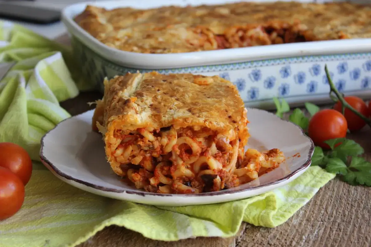 Una fetta di pasta al forno con pomodori, carne e pasta corta, un classico della cucina pugliese.