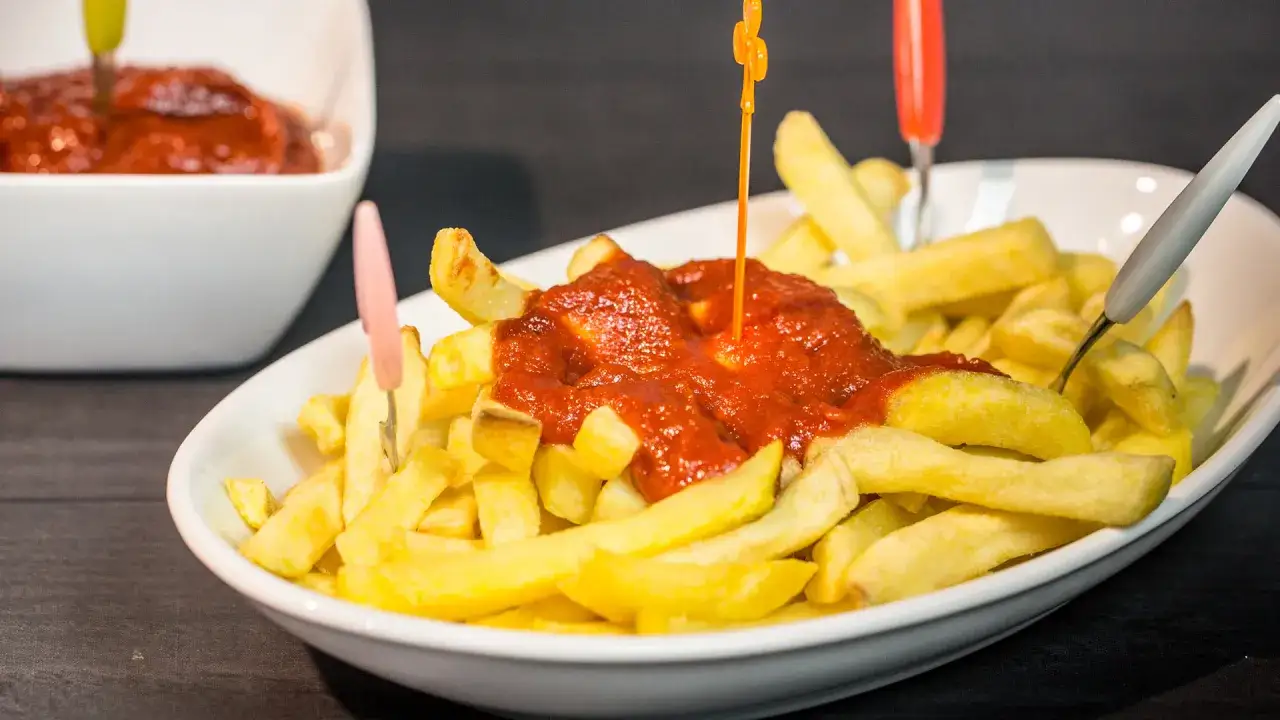 Patatine fritte dorate con una generosa porzione di ketchup fatto in casa, servite con stuzzicadenti colorati.