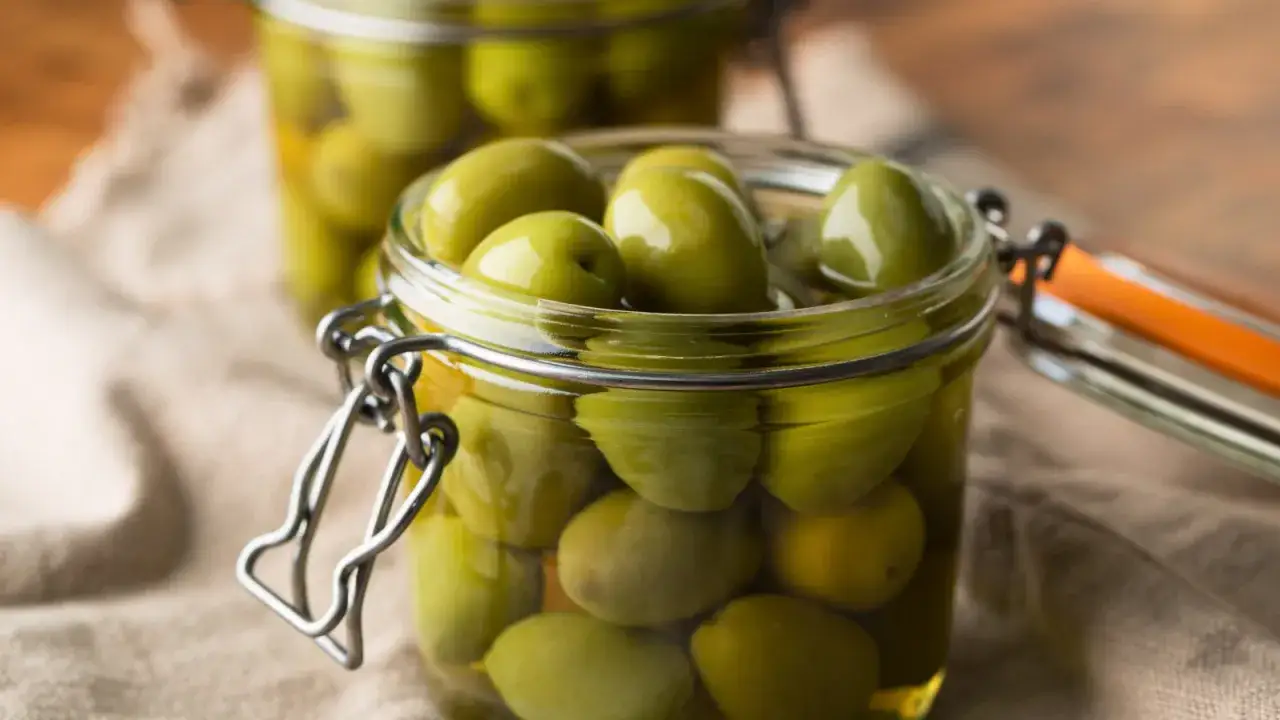 Vasi di vetro con olive verdi immerse nella salamoia per olive, pronte per essere gustate.