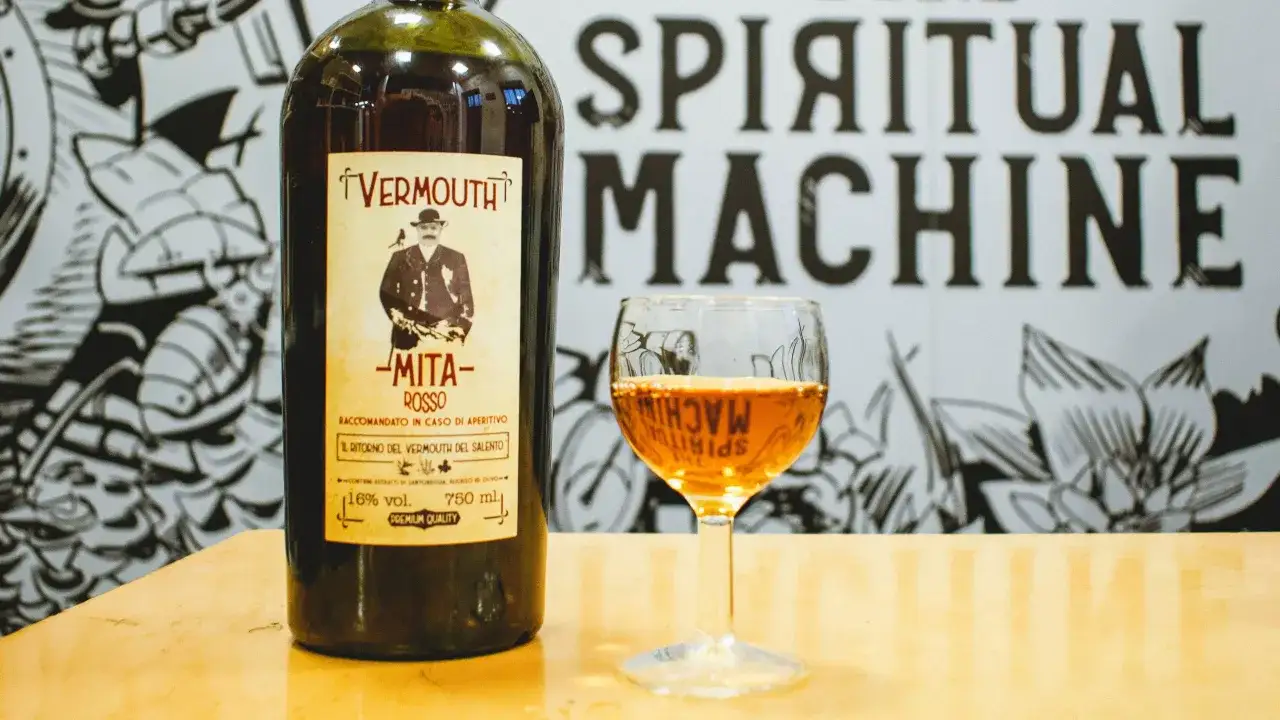Bottiglia di vermouth rosso Mita e un bicchiere pieno. Scopri come si fa il vermouth con questo aperitivo tradizionale.