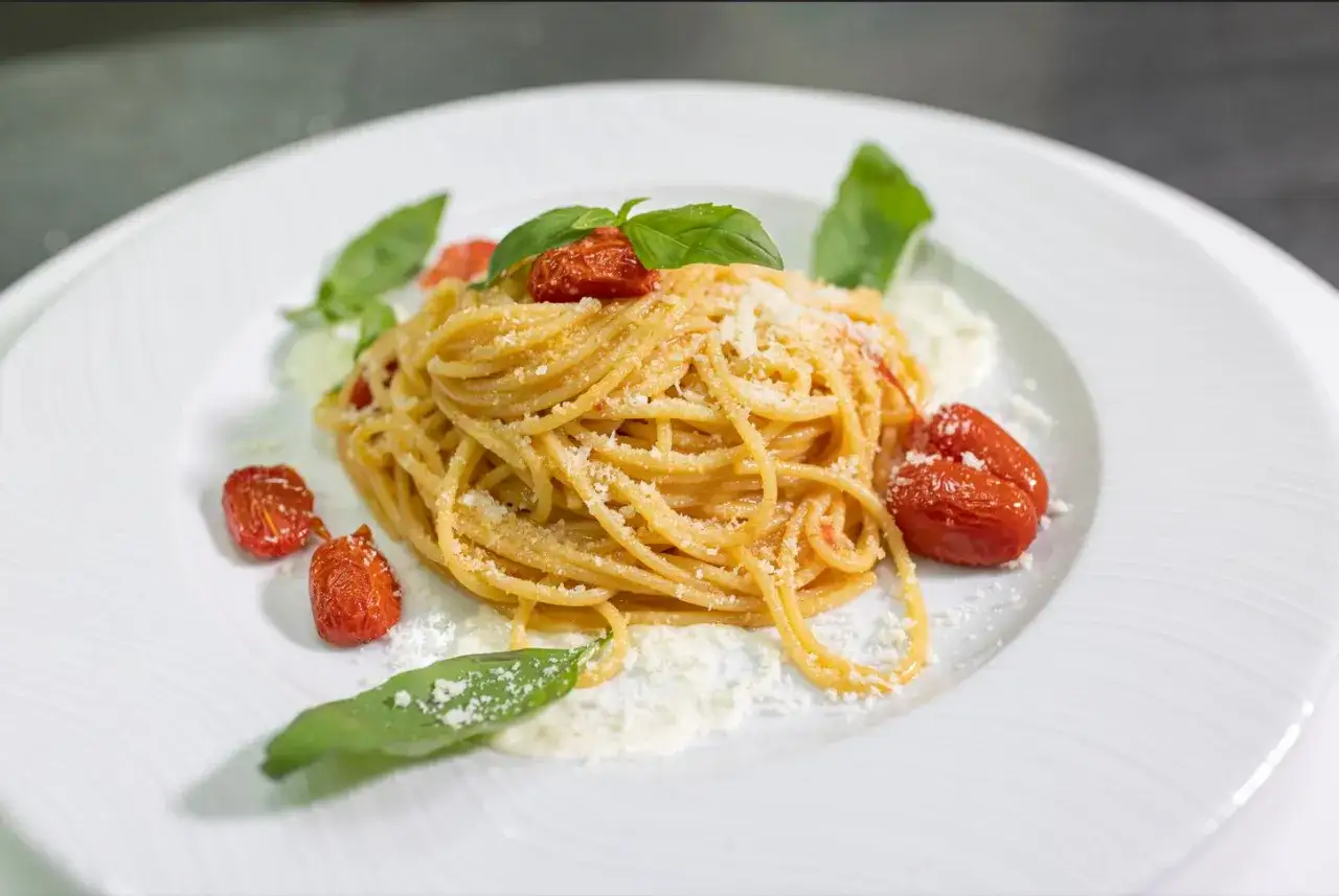 Spaghetti con pomodorini confit, basilico e parmigiano, un piatto che ricorda la scarpariello ricetta.