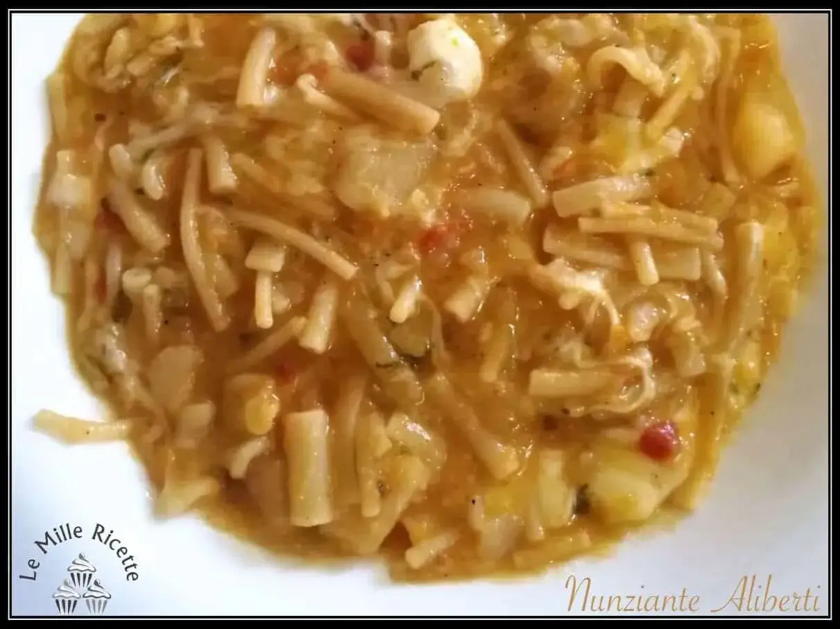 Un piatto fumante di pasta e patate alla napoletana, con pezzi di formaggio filante e pomodoro.