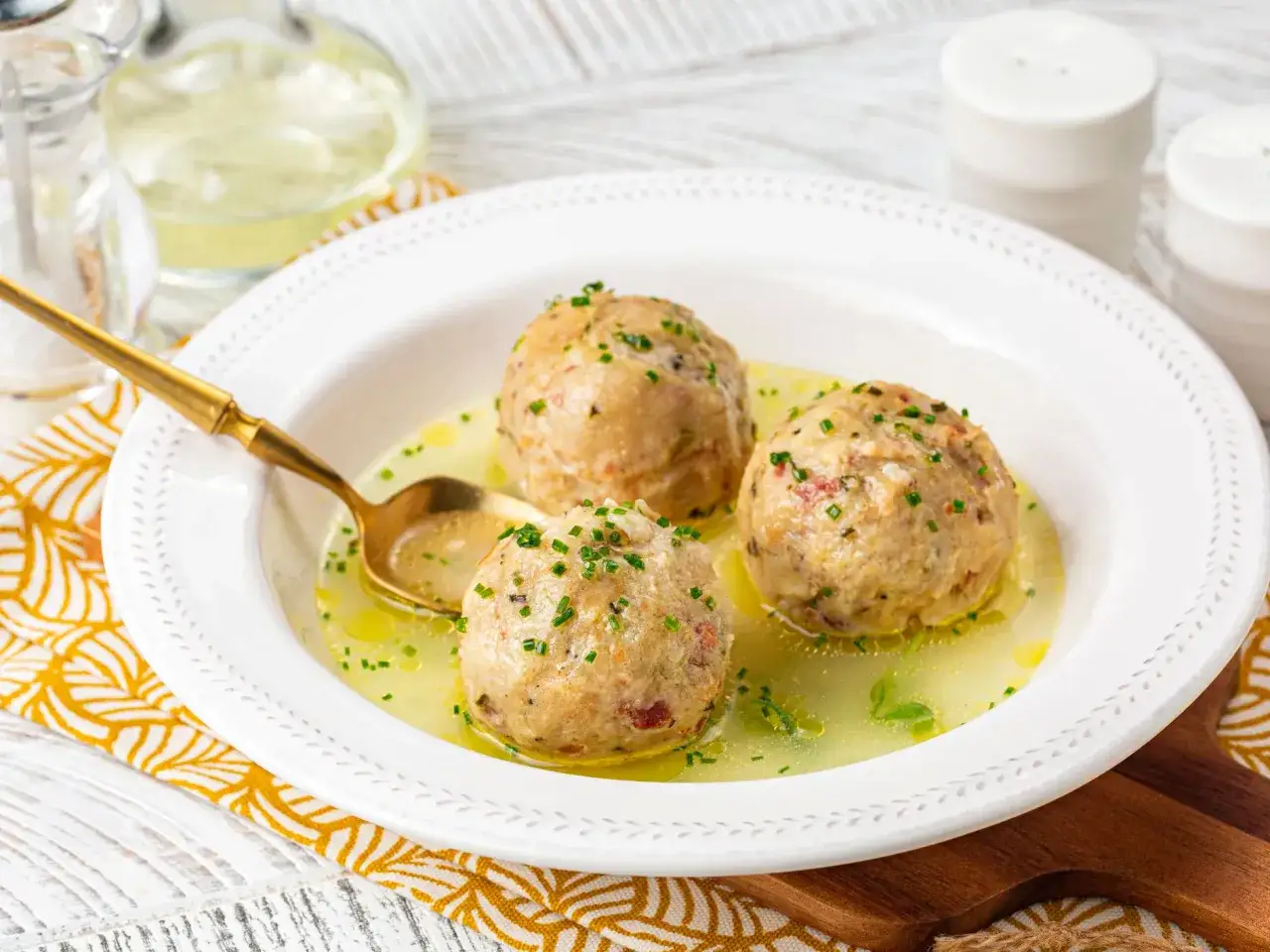 Tre canederli in brodo, un classico delle ricette con pane raffermo, guarniti con erba cipollina.