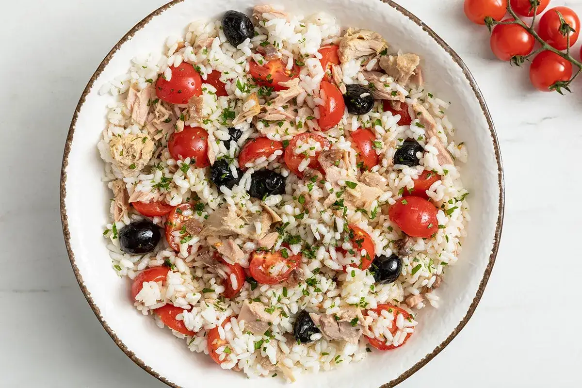 Insalata di riso freddo con tonno, pomodorini e olive nere. Un'idea fresca per le tue ricette estive.