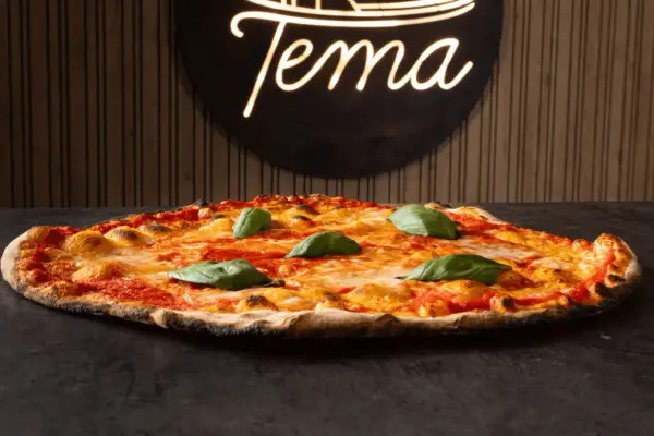 Pizza romana con pomodoro, mozzarella filante e basilico fresco. Ingredienti semplici per un gusto autentico.