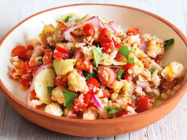 Panzanella ricetta: un'insalata estiva con pane raffermo, pomodori, cetrioli, cipolla rossa e basilico, condita con olio d'oliva.