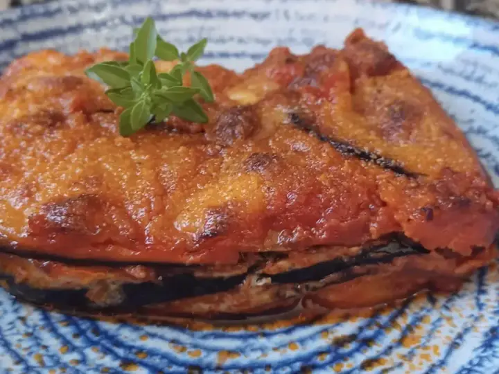 Parmigiana in padella, uno strato di melanzane fritte, pomodoro e formaggio, guarnita con basilico fresco.