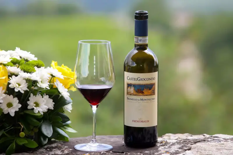 Un bicchiere di Brunello di Montalcino e un mazzo di fiori gialli e bianchi. Perfetti abbinamenti per una cena speciale.